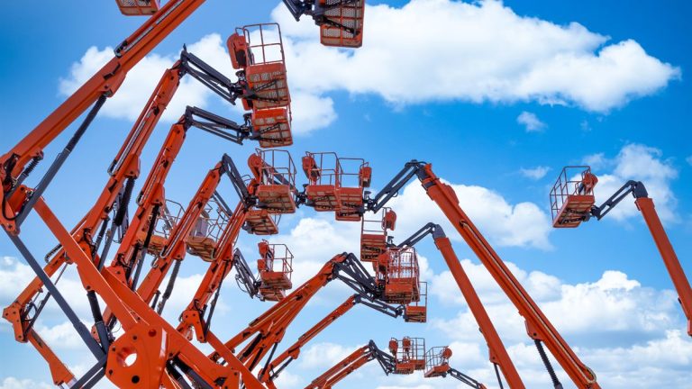 Row of aerial work platforms lined up against a blue sky