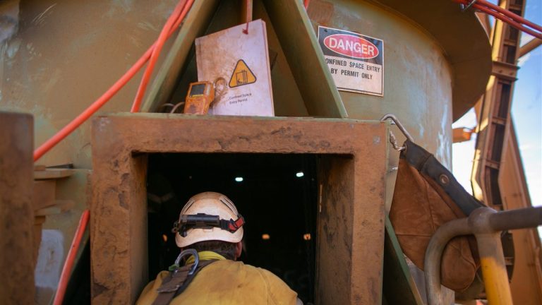 Confined space entry point with danger sign, gas detector, and attendant