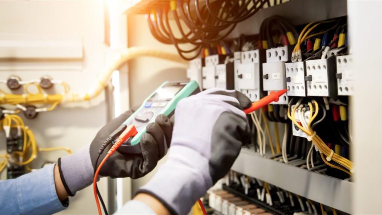 Electrical worker measuring voltage at a main distribution board