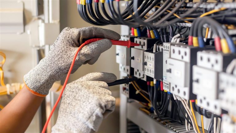 Electrician testing an electrical control cabinet with a multimeter