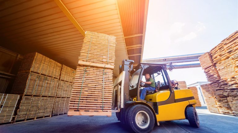 Forklift moving lumber in an outdoor yard